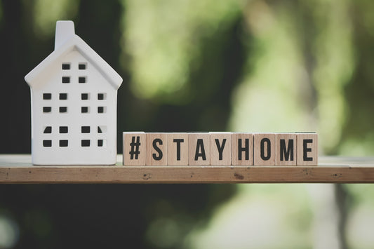 a wooden block that says stay home next to a house